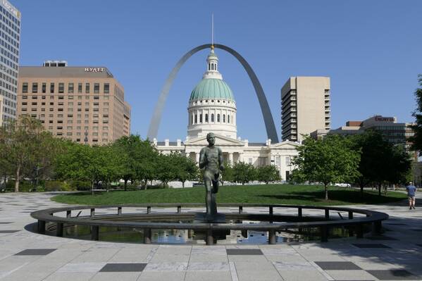 photographer Bitten by the Bug travel  photo. the statue in the foreground is the olympic runner commemorating the st louis olympics of 1904  beyond that is the old courthouse and then the gateway arch which stands on the banks of the mississippi river.